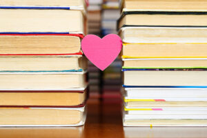a small heart hangs between two piles of old books.